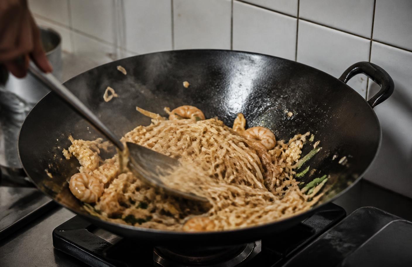Soaked flat rice noodles tossed with shrimp and scrambled egg in a hot carbon steel wok with steam rising