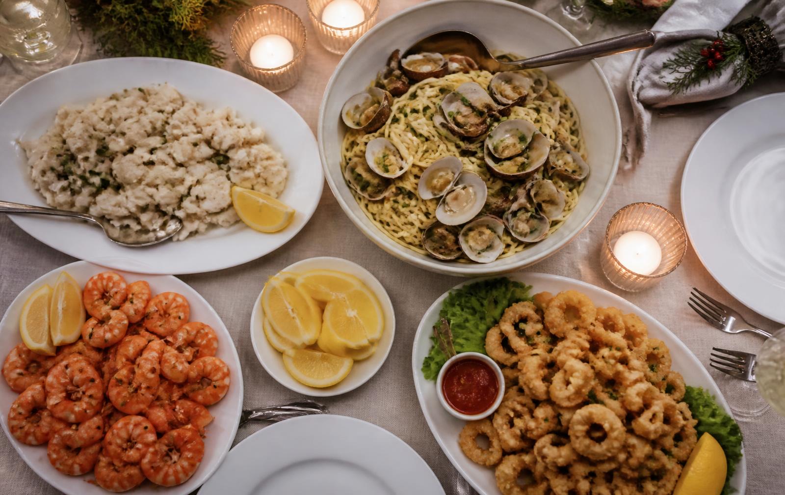 A candlelit Christmas Eve table set with baccala salad, linguine with clams, fried calamari, and shrimp